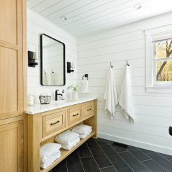 A contemporary modern bathroom design for a country home cabin. featuring a  classic freestanding vanity and linen storage cabinet.